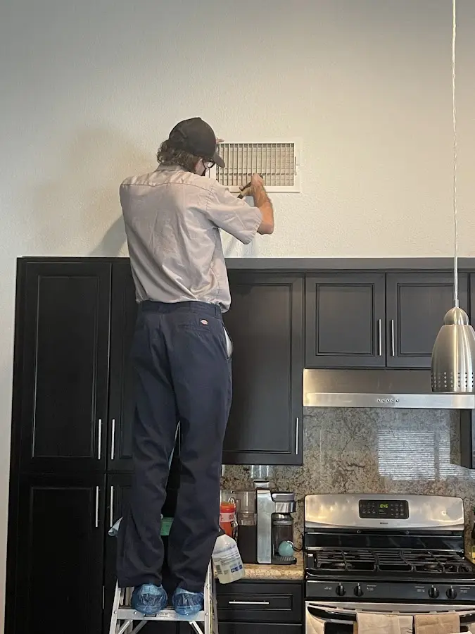 Technician inspecting an air vent during HVAC service in Monessen